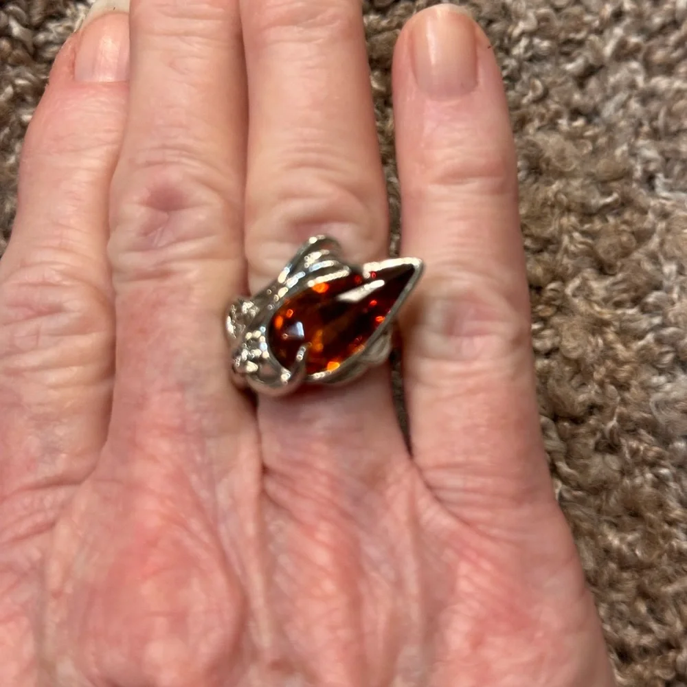Ring in silver metal intricate with teardrop shaped amber color stone